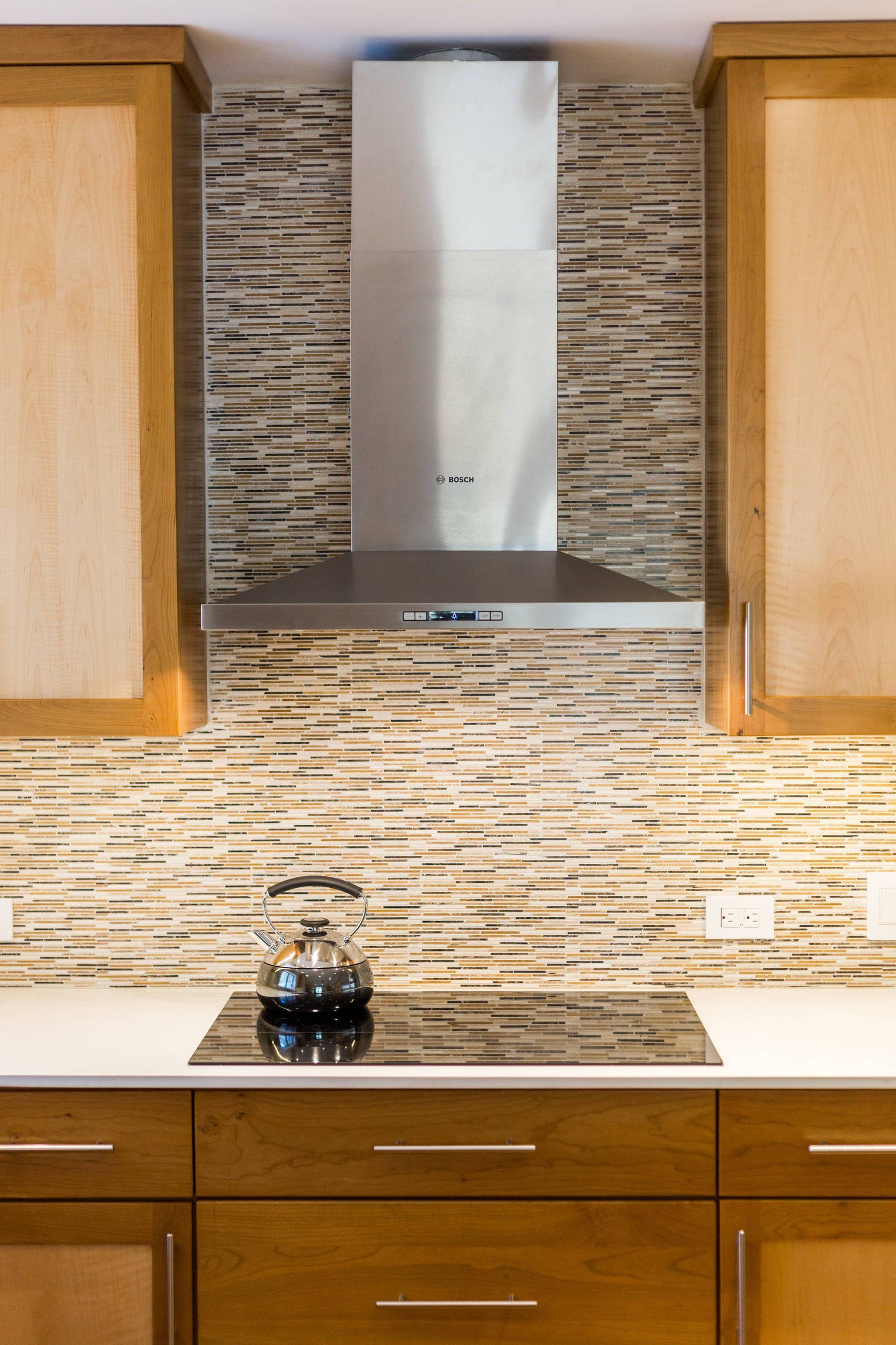 A kitchen with a stove top oven and a stainless steel hood